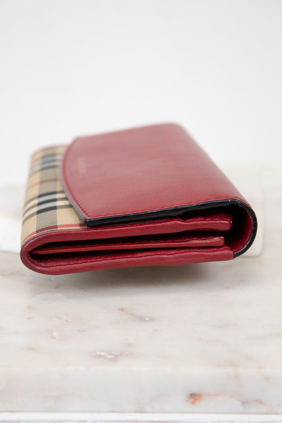 Red wallet with checkered pattern on a marble surface