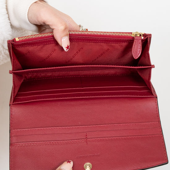 Red handbag held open by a person with a white background
