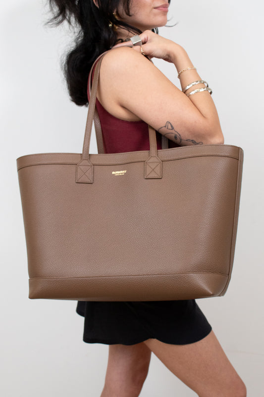 Person holding brown leather tote on white background