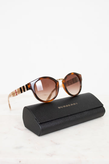 Tortoiseshell sunglasses with a black case on a white background