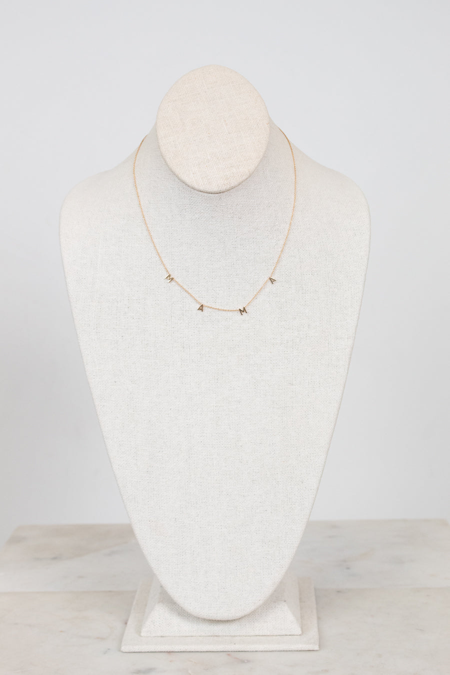 Gold necklace on a white mannequin bust against a white background