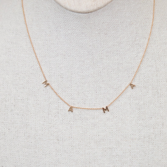 Gold necklace with "MAMA" letters on cream bust