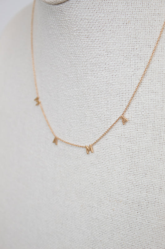 Gold necklace with "MAMA" letters on cream bust