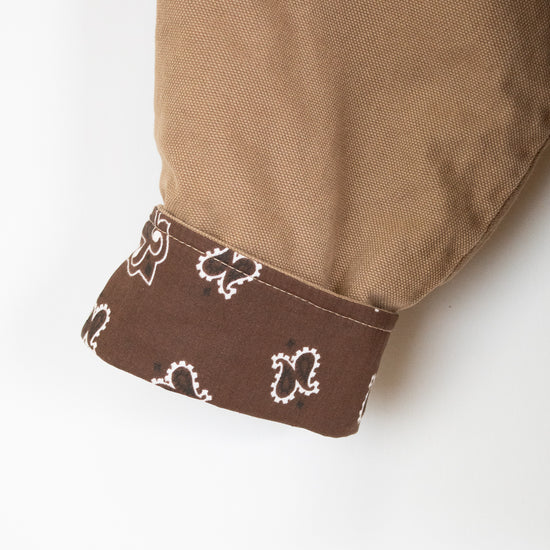 Close-up of a brown fabric with a patterned trim on a white background