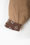 Close-up of a brown fabric with a patterned trim on a white background