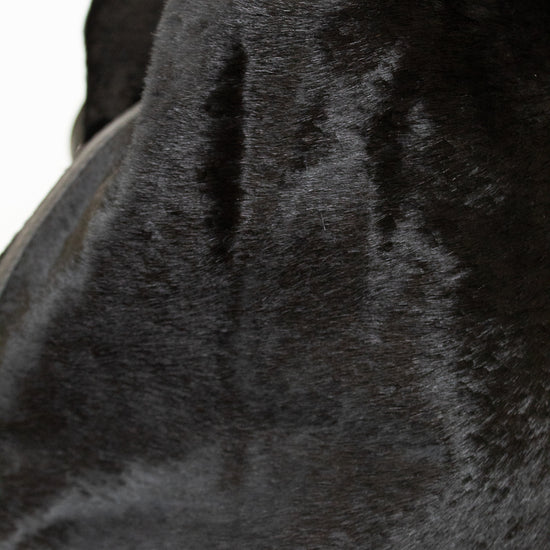 Close-up of a black faux fur handbag or purse showing the soft textured material and a dark handle against a plain white background.