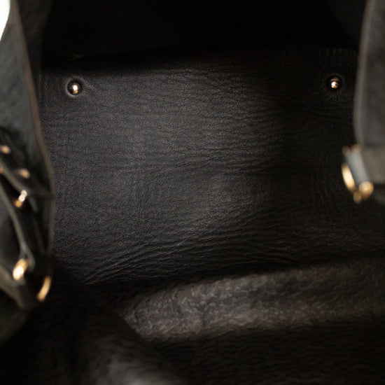 Close-up of the interior of a black textured leather bag, showing the black leather lining, metal rivets, and a sliver of the black exterior material with gold-tone hardware on the sides.