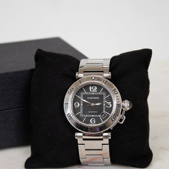 Silver Cartier watch on a black cushion with a white background