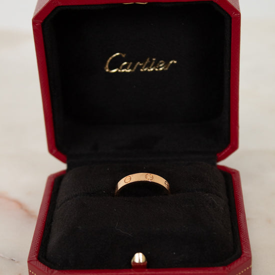 Rose gold ring in a red Cartier box on a marble surface