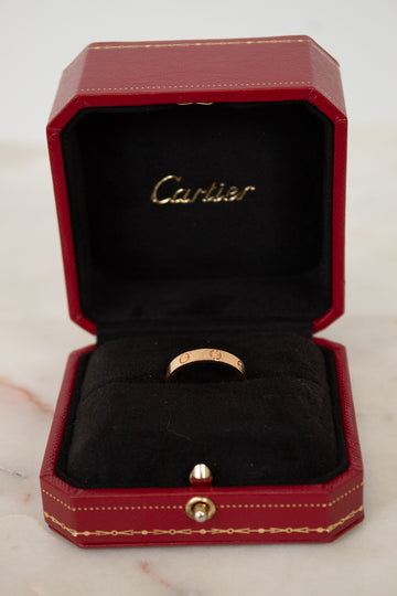 Rose gold ring in a red Cartier box on a marble surface