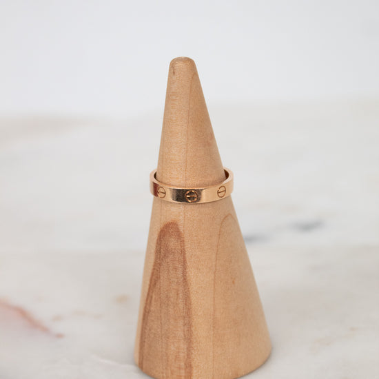 Wooden cone with a rose gold ring on a marble surface