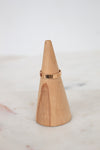 Wooden cone with a rose gold ring on a marble surface