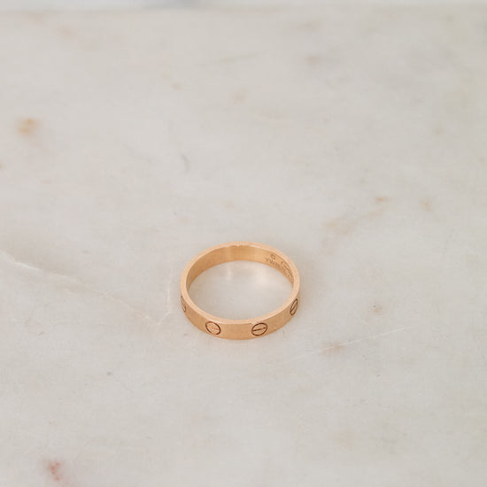 Rose gold ring with engraved details on a marble surface