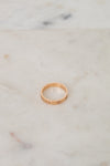 Rose gold ring with engraved details on a marble surface