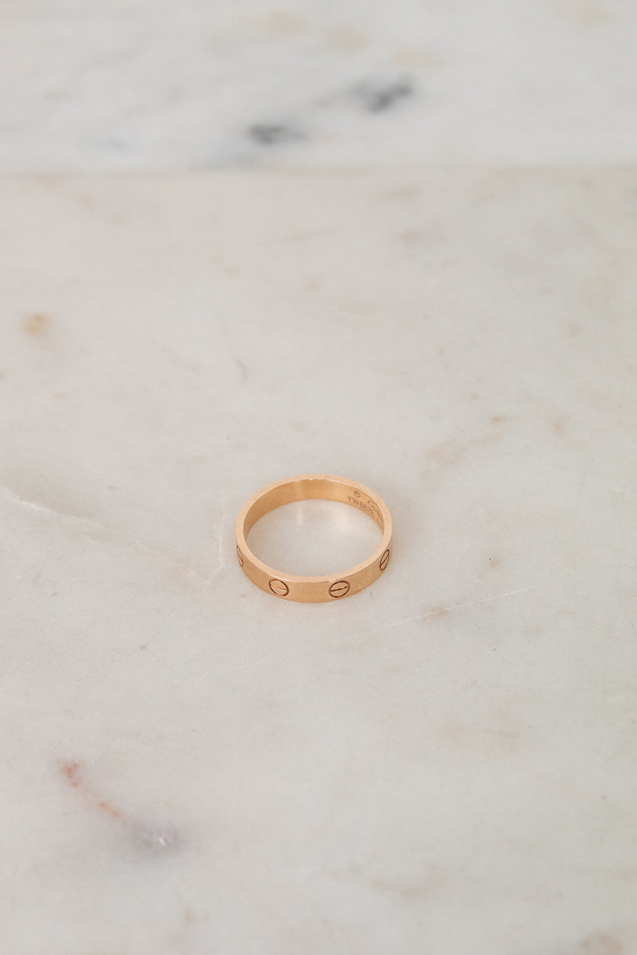 Rose gold ring with engraved details on a marble surface