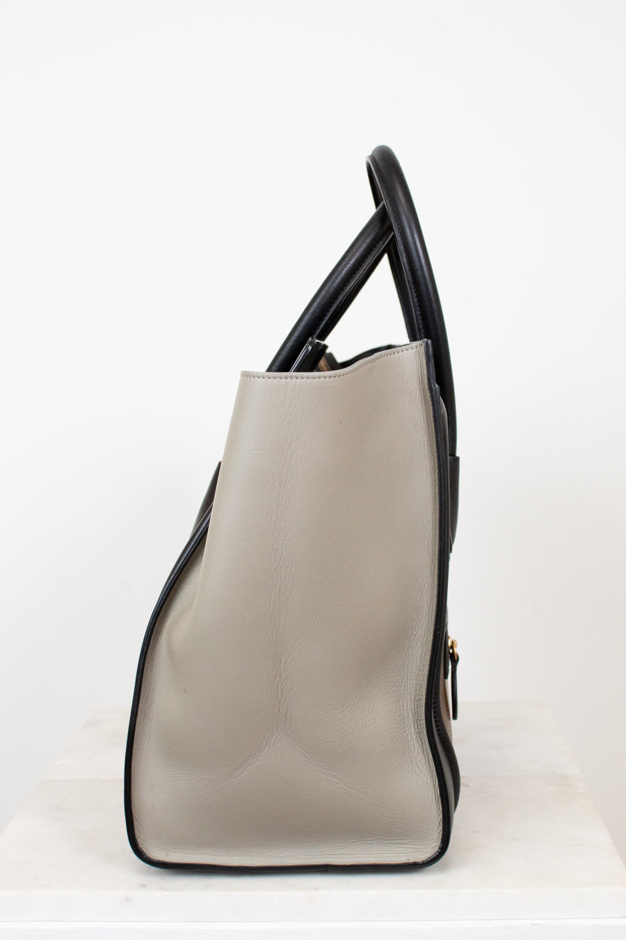 Beige handbag with black accents on a white background