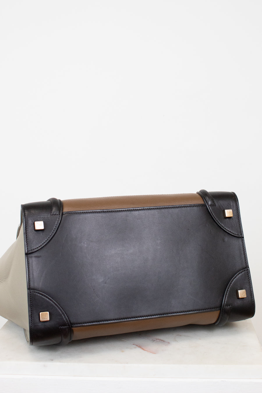 Black leather base of tote bag with brown accents on a white background