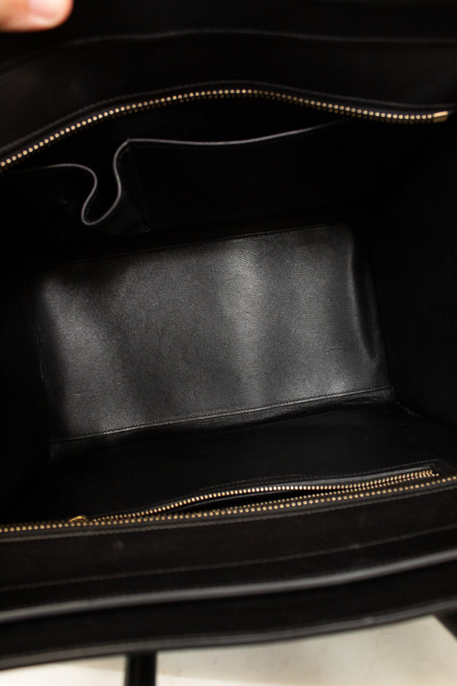 Black leather inside of handbag with gold zipper.