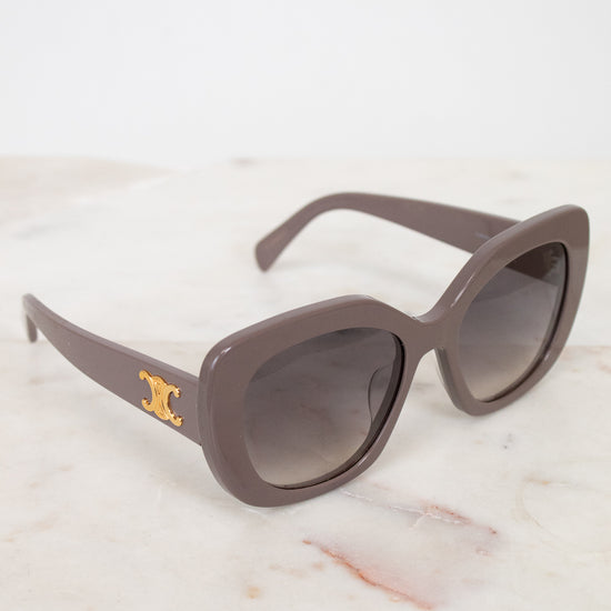 Sunglasses with a gold logo on a marble surface
