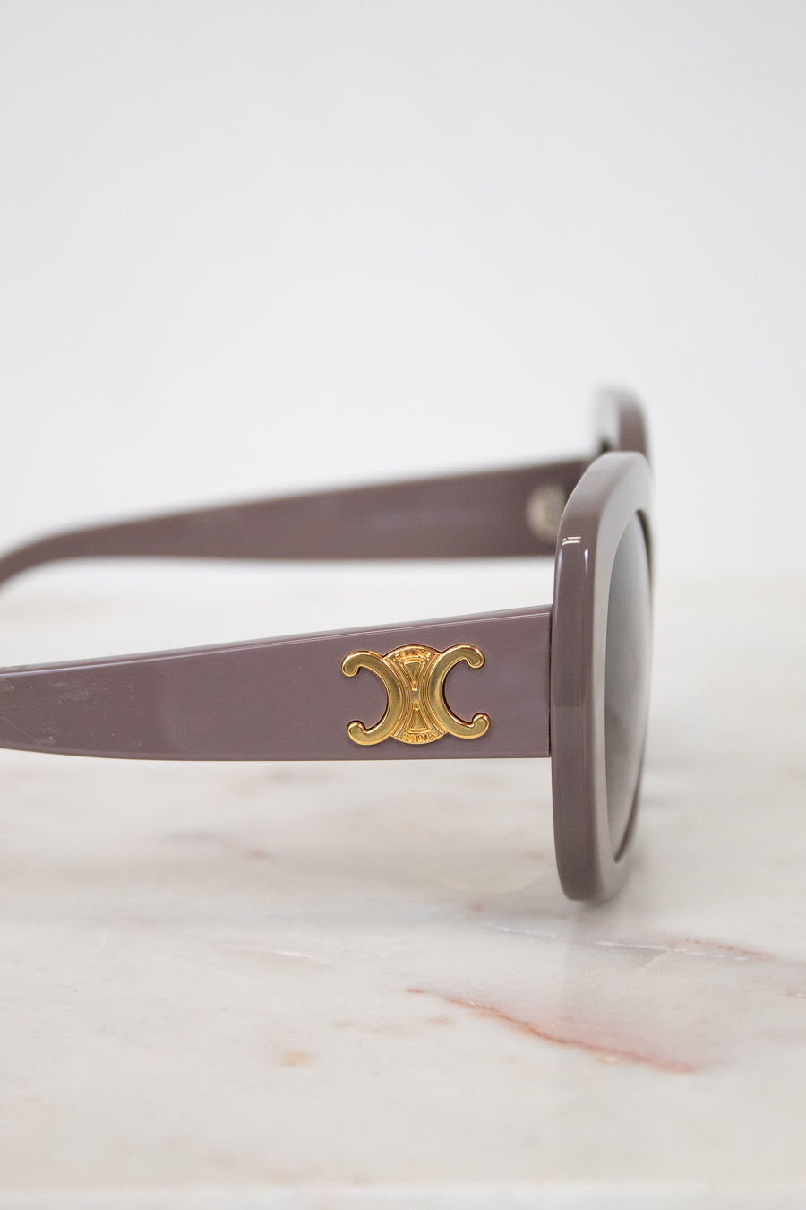 Sunglasses with a gold logo on a marble surface