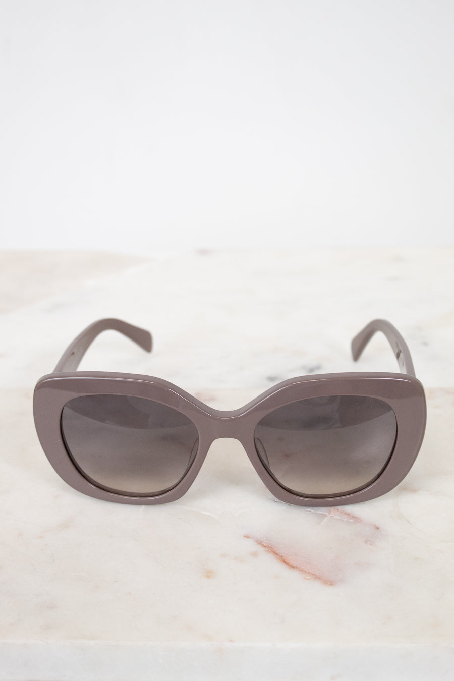 Cat-eye sunglasses with a gradient lens on a marble surface