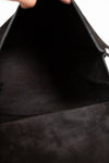 Close-up of a black leather bag with a hand holding it open.