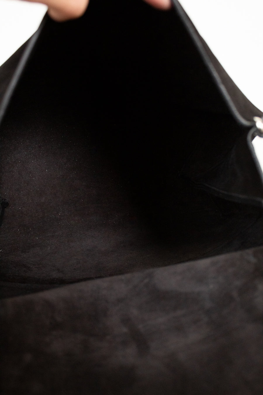 Close-up of a black leather bag with a hand holding it open.