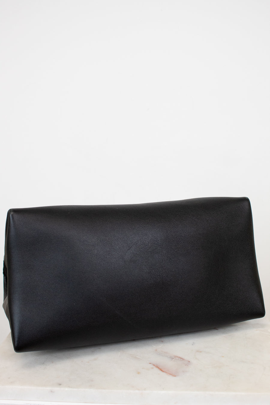 Black leather base of bag on a light marble surface