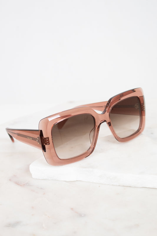 Pink-tone translucent sunglasses on a white background