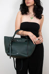 Woman holding a green handbag against a white background