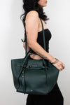 Person holding a dark green handbag against a white background