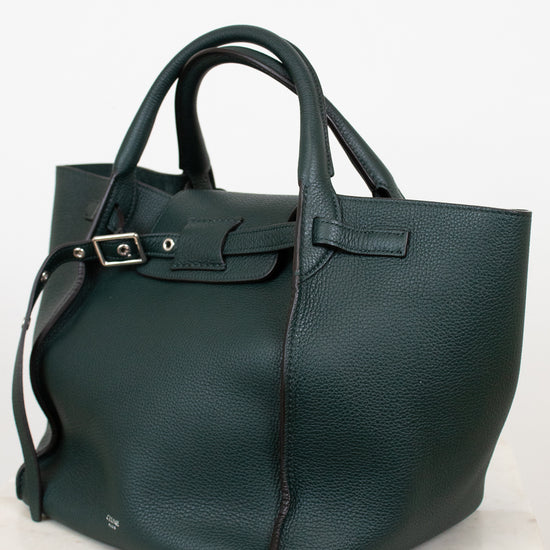 Green leather handbag on a light marble surface with a white background