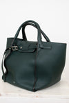 Green leather handbag on a light marble surface with a white background