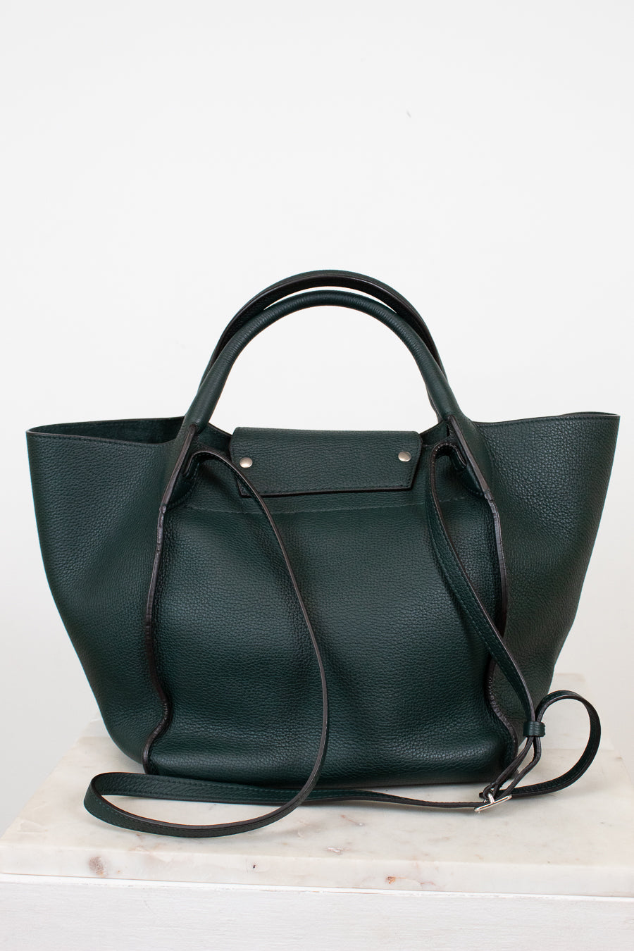 Dark green leather handbag with a shoulder strap on a white background