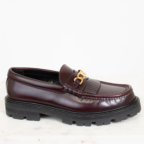 Brown loafer shoe with gold buckle on a white background