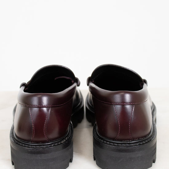 Pair of brown leather shoes with thick black soles on a light background