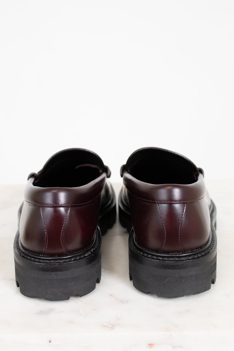 Pair of brown leather shoes with thick black soles on a light background