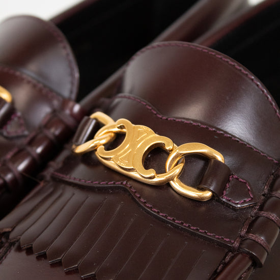 Brown loafers with gold chain detail on a white background
