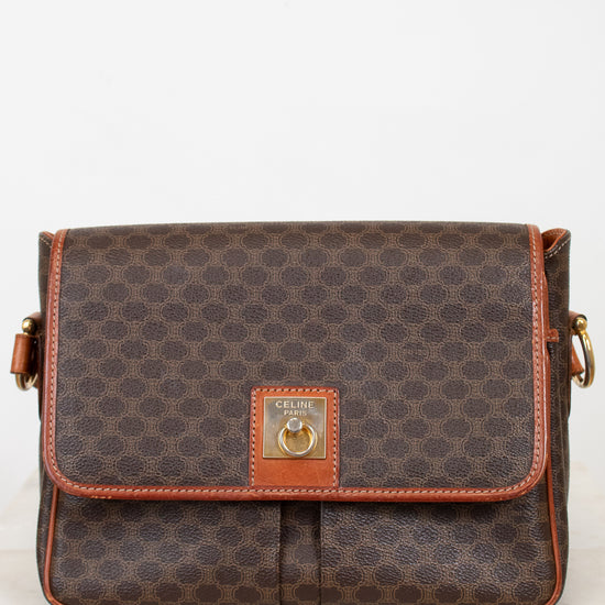 Brown patterned handbag with gold accents on a white background