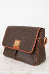 Brown patterned handbag with gold accents on a light background