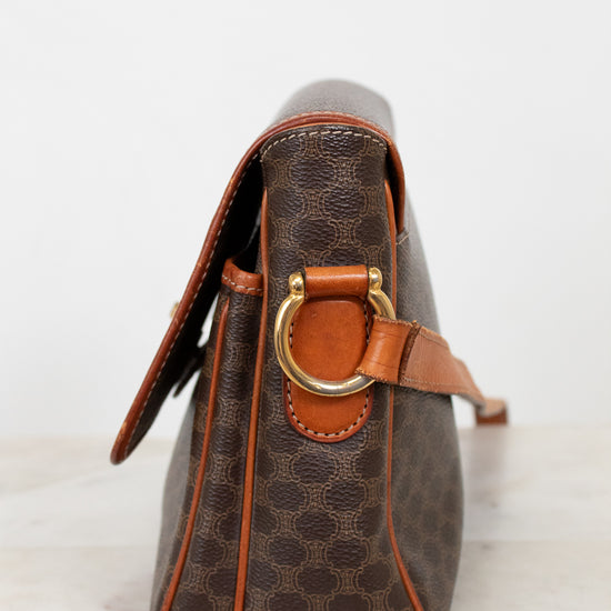 Brown leather handbag with gold clasp on a light background