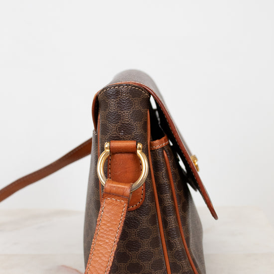Brown leather handbag with gold hardware on a light background