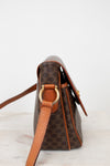 Brown leather handbag with gold hardware on a light background