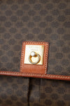 Close-up of a Celine bag with logo plaque on brown patterned fabric