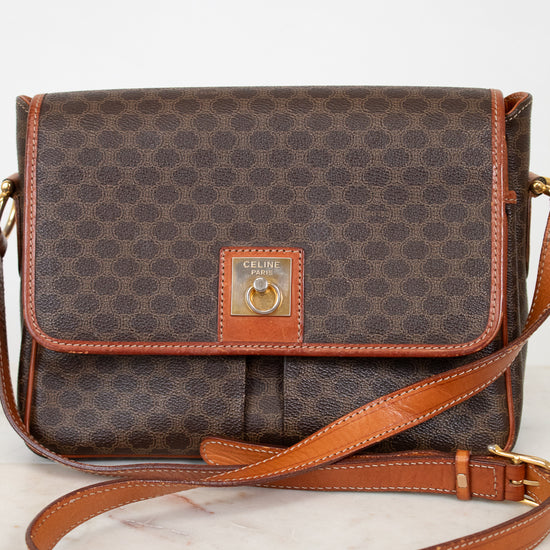 Brown patterned handbag with tan leather strap and accents on a white background