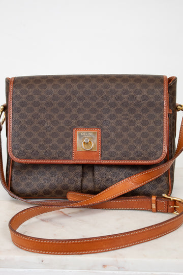 Brown patterned handbag with tan leather strap and accents on a white background