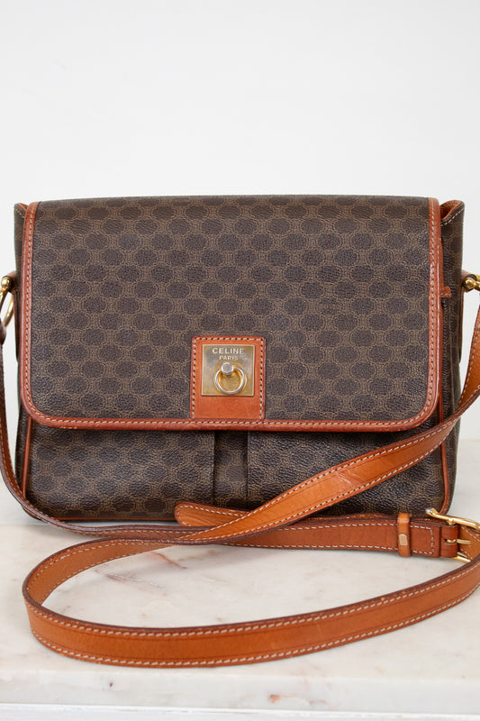 Brown patterned handbag with tan leather strap and accents on a white background