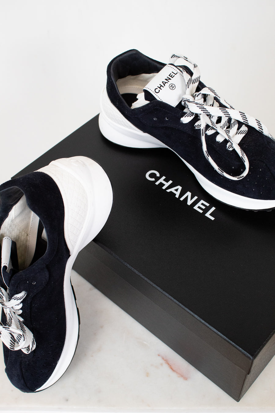 Chanel sneakers on a black box with a white background