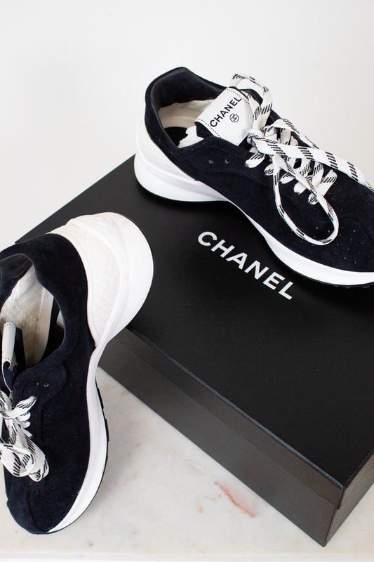 Chanel sneakers on a black box with a white background
