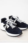 Pair of Chanel navy blue sneakers with white laces on a light gray background
